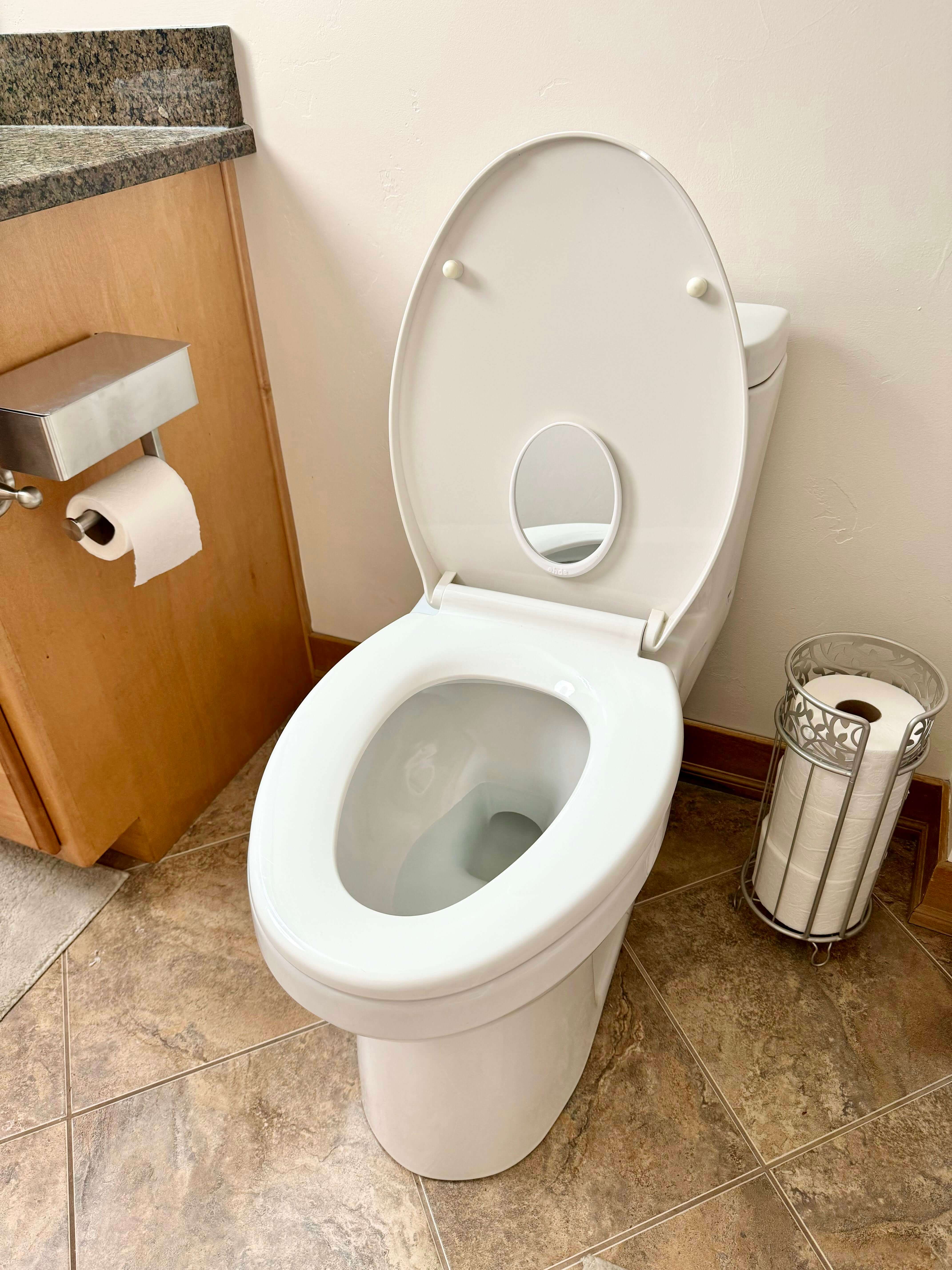 White toilet with an attached mirror on the lid, designed to help with bathroom independence, personal hygiene, and potty training